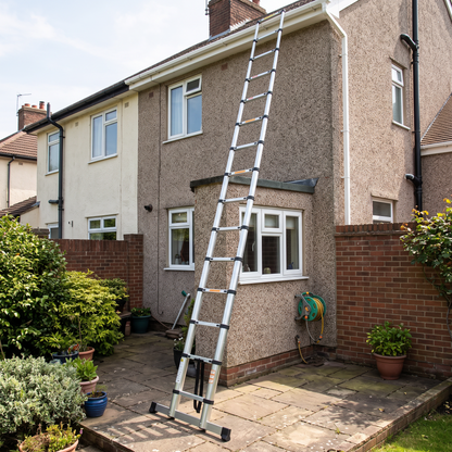 Telescopic ladder leaning against a house wall up to the guttering