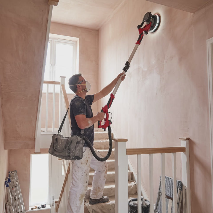 Long-reach drywall sander on a tall stairwell wall